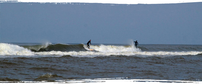 Surfer in den Wellen von Petten, Nordholland.