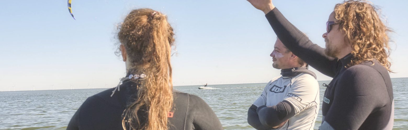Kitekurs in der Kleingruppe: Lehrer erklaert die Kite-Steuerung direkt im Wasser