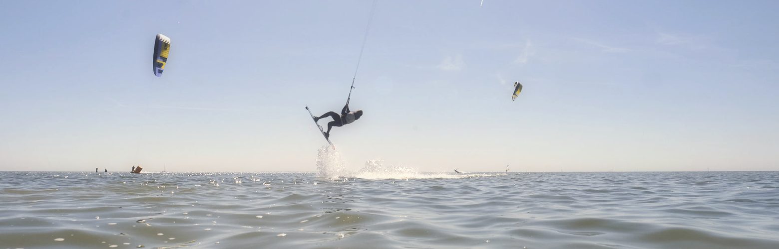 Kitesurfer springt ueber das flache Wasser des IJsselmeers