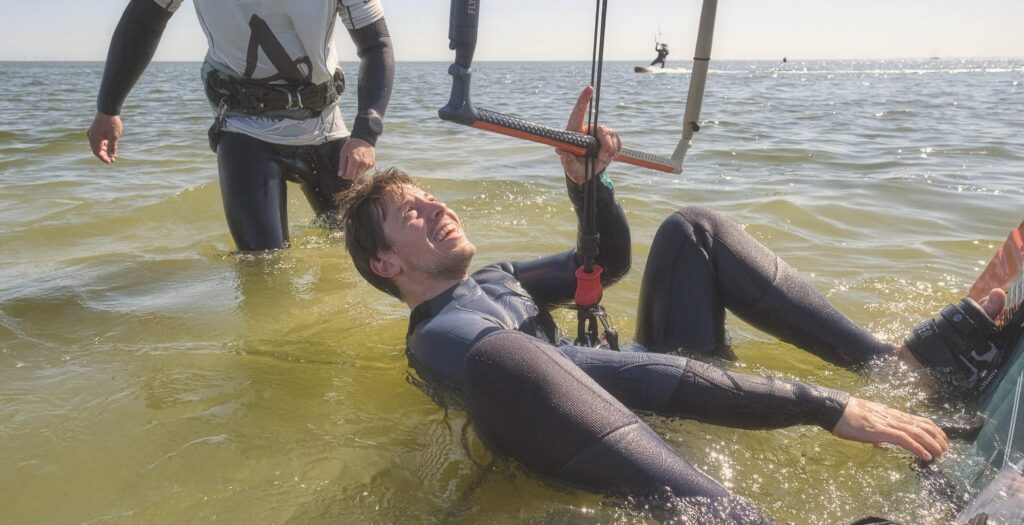 Kitesurfen lernen im Stehrevier: Schueler uebt den Wasserstart mit Lehrer im flachen IJsselmeer