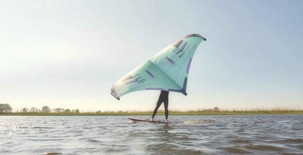 Wingfoiler steht mit Wing auf dem Board im flachen IJsselmeer bei Workum