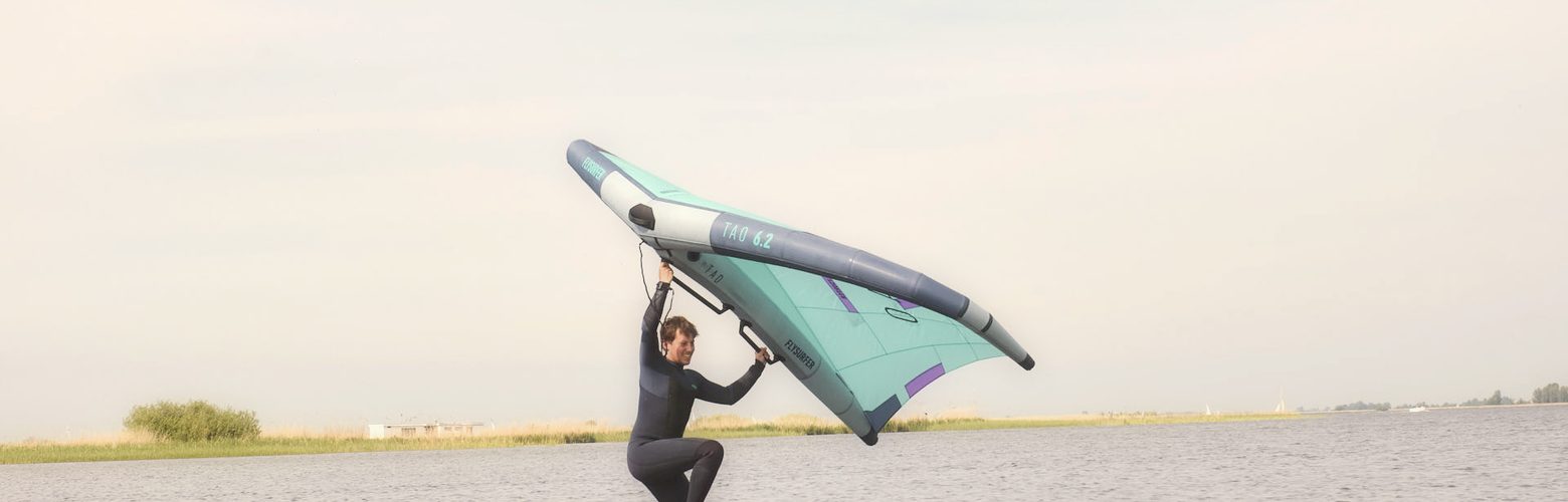Wingfoil Einsteiger uebt Wingsurfen auf dem grossen Board ohne Foil im Stehrevier